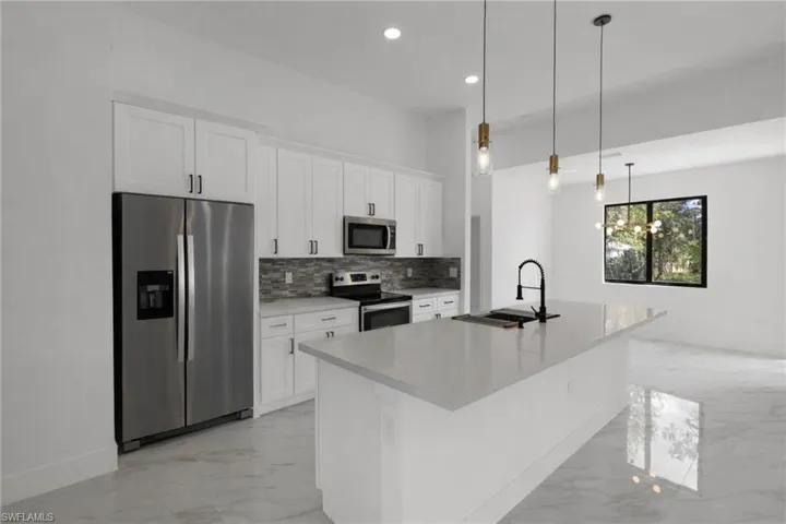 Kitchen featuring stainless steel appliances, white cabinets, and light marble finish floors