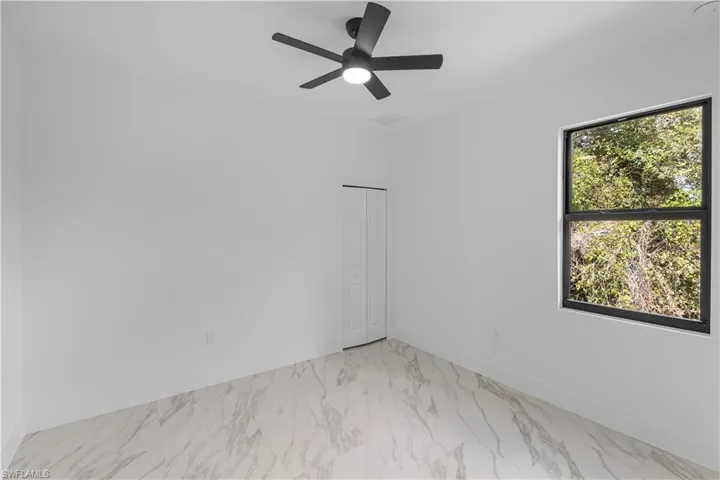 Unfurnished room featuring light marble finish floors and a ceiling fan