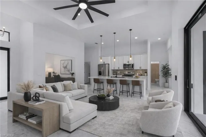 Living area with a tray ceiling, light marble finish floors, ceiling fan, and recessed lighting
