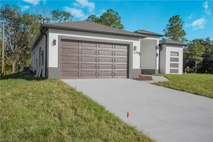 View of front facade featuring stucco siding, a front lawn, driveway, and an attached garage