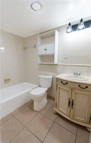 The bathroom features a tiled floor, a white bathtub, a toilet, and a vanity with a sink and storage