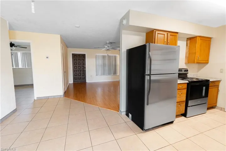 The kitchen features tile flooring, wood cabinetry, a stainless steel refrigerator, and a range