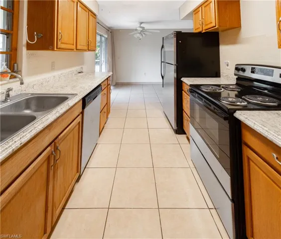 The kitchen features wood cabinetry, granite-style countertops, and a double basin stainless steel sink