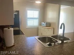 Kitchen with dark countertops, a peninsula, and stainless steel refrigerator
