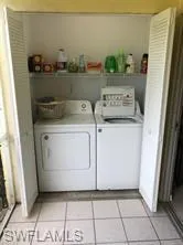 Laundry area with separate washer and dryer and light tile patterned flooring