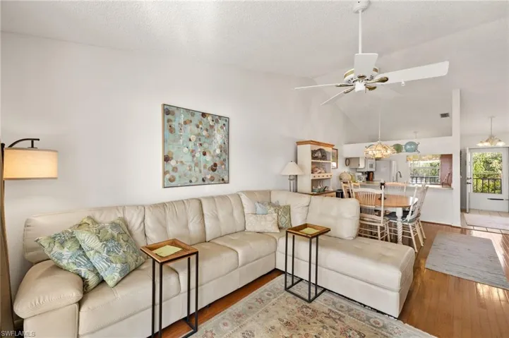 Living area featuring lofted ceiling, a textured ceiling, wood finished floors, and a ceiling fan
