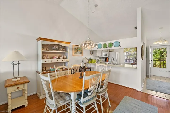 Dining space featuring high vaulted ceiling, visible vents, baseboards, light wood-type flooring, and a notable chandelier