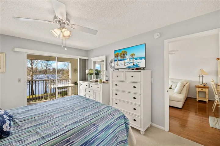 Bedroom featuring light carpet, a textured ceiling, access to outside, baseboards, and ceiling fan