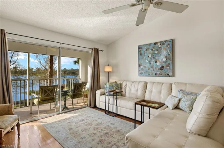 Living area with lofted ceiling, a textured ceiling, wood finished floors, and a ceiling fan