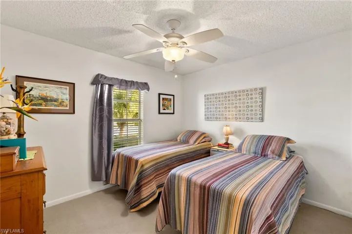 Bedroom featuring light carpet, baseboards, a ceiling fan, and a textured ceiling
