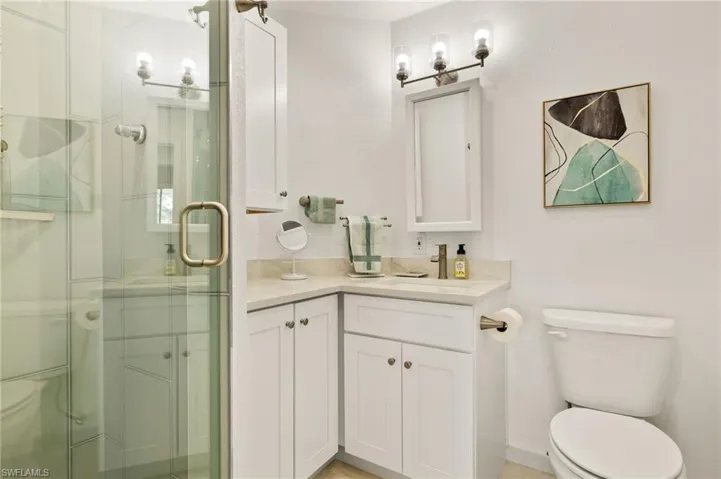 Full bath featuring vanity, toilet, and a shower stall
