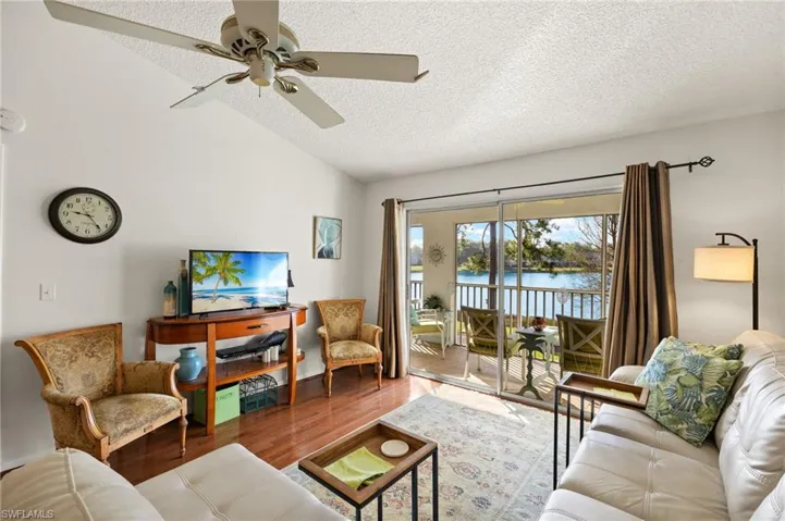 Living area with lofted ceiling, a textured ceiling, wood finished floors, and a ceiling fan