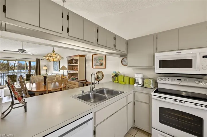 Kitchen with white appliances, light countertops, a sink, and a textured ceiling