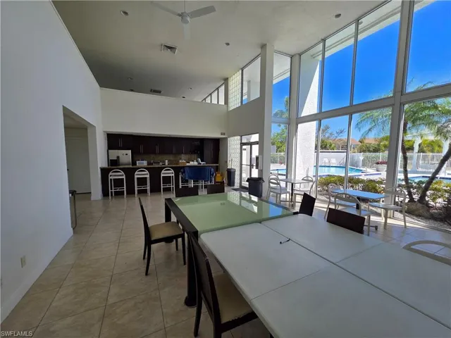 Dining space featuring a high ceiling, ceiling fan, light tile patterned flooring, and expansive windows