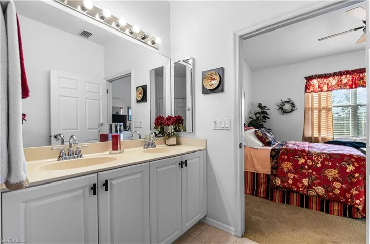 Main Full bath with ensuite bathroom, double vanity, ceiling fan, light carpet, and light tile patterned floors