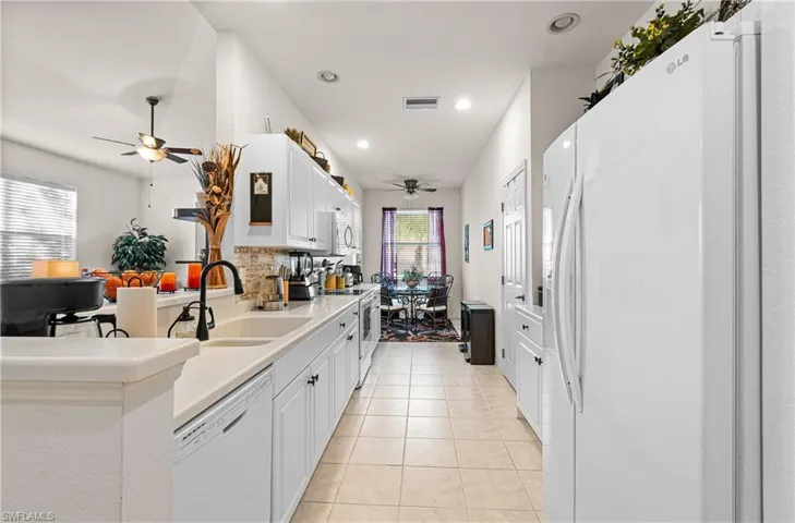 Kitchen featuring ceiling fan, white appliances, white cabinetry, light countertops, and light tile patterned floors