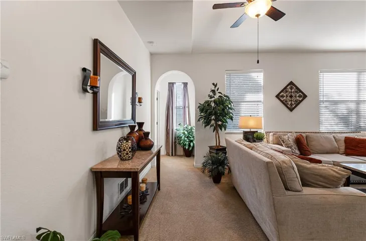 Living room with arched walkways, a ceiling fan, and carpet flooring