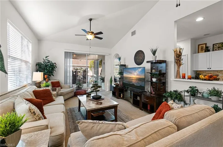 Living area featuring ceiling fan, lofted ceiling, and light carpet