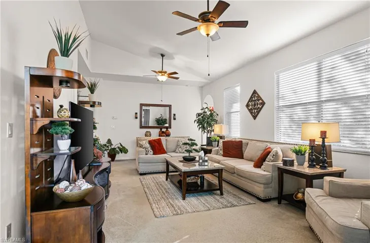 Living area featuring carpet, a ceiling fan, and vaulted ceiling