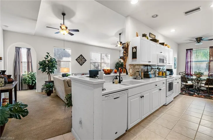 Kitchen featuring a ceiling fan, open floor plan, white appliances, light countertops, and tasteful backsplash