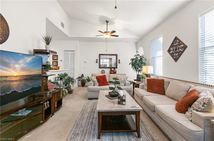 Carpeted living room with lofted ceiling and ceiling fan