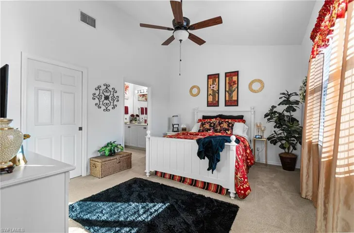 Main Bedroom featuring light carpet, lofted ceiling, a ceiling fan, and ensuite bath