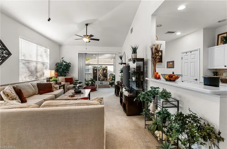 Living room featuring light colored carpet, a ceiling fan, and lofted ceiling