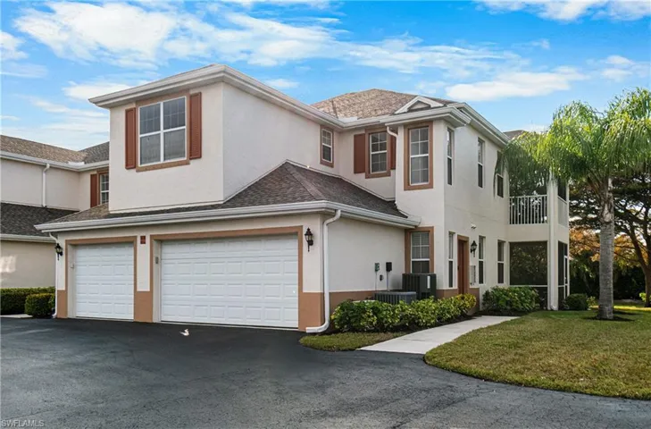 Traditional-style house with stucco siding, a garage, a balcony, and driveway
