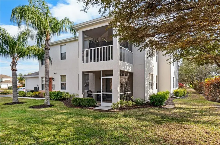 Back of house with a sunroom, stucco siding, a balcony, and a lawn