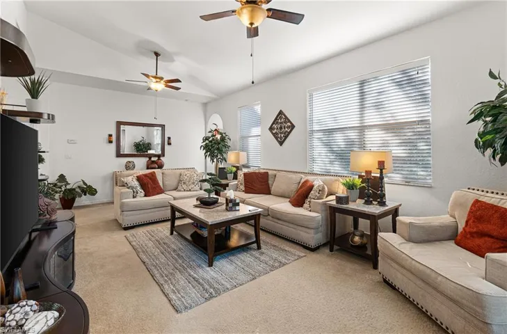 Carpeted living area with a ceiling fan and vaulted ceiling