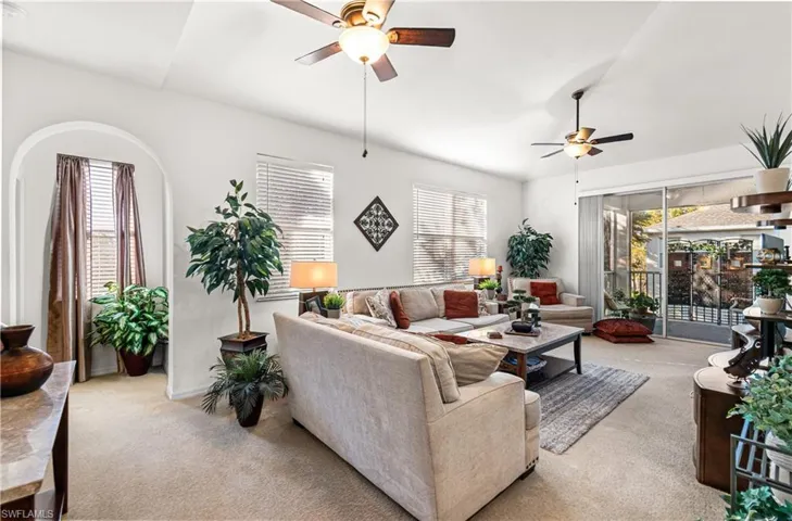 Carpeted living area featuring healthy amount of natural light, a ceiling fan, and lofted ceiling