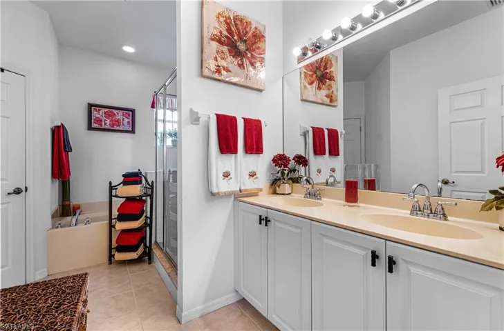 Main Bathroom with double vanity, a shower stall, light tile patterned floors, and a bath
