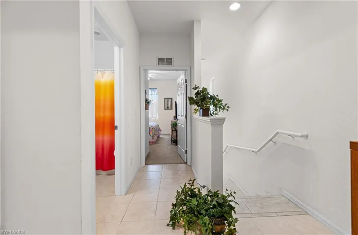 Corridor featuring an upstairs landing and light tile patterned floors