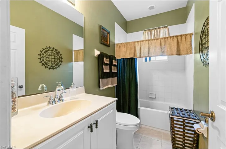 Guest bath 2 Bathroom with vanity, shower / bathtub combination with curtain, and light tile patterned flooring