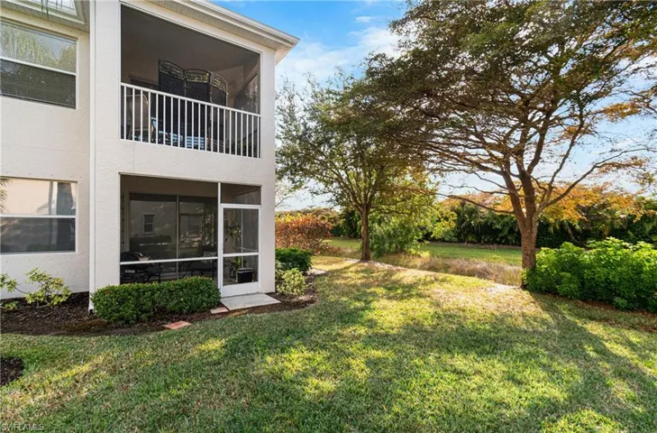 View of green lawn with a sunroom and a balcony