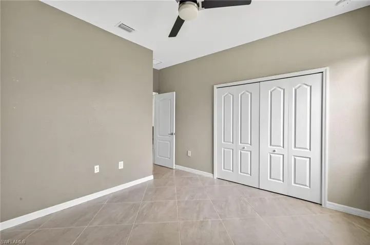 Unfurnished bedroom with light tile patterned flooring, a closet, and a ceiling fan