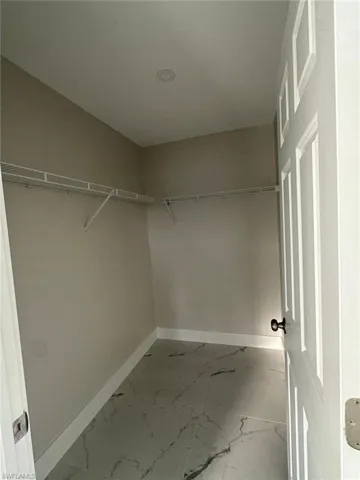 Walk in closet with light marble finish floors