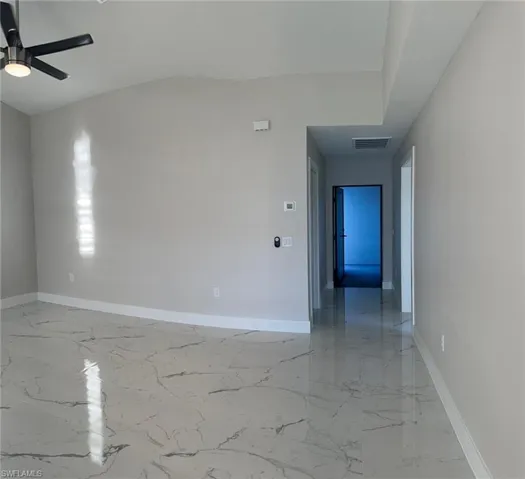 Unfurnished room featuring light marble finish flooring, ceiling fan, and vaulted ceiling
