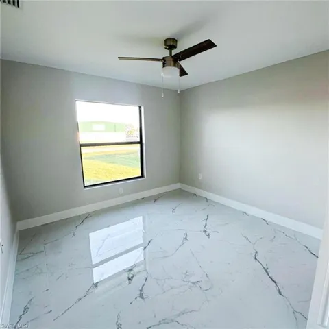 Spare room featuring baseboards and light marble finish floors