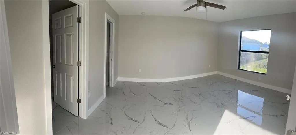 Spare room with light marble finish flooring and a ceiling fan