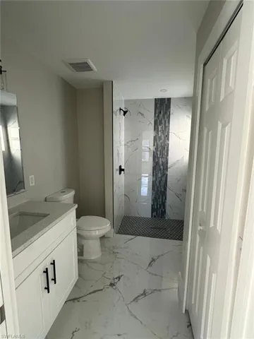 Full bathroom with a marble finish shower, vanity, and light marble finish flooring