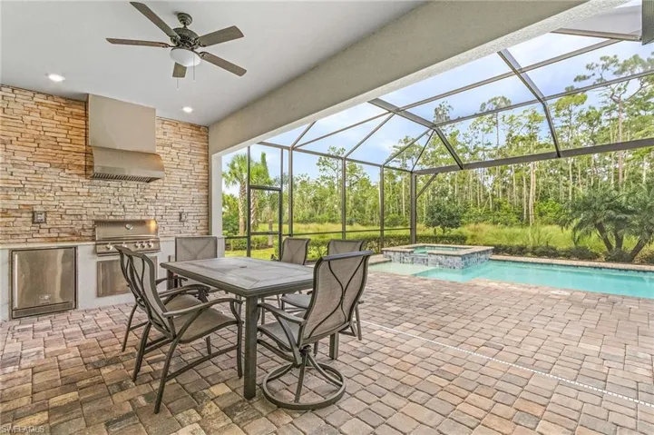 View of pool with ceiling fan, an in ground hot tub, glass enclosure, a patio, and grilling area