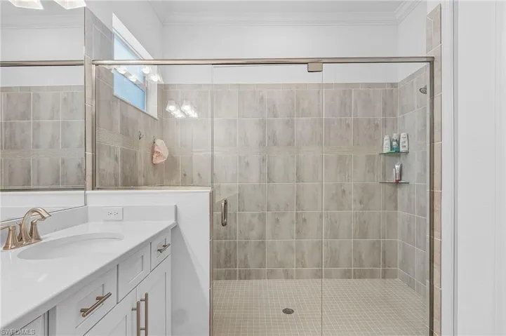 Bathroom with crown molding, vanity, and a shower with shower door