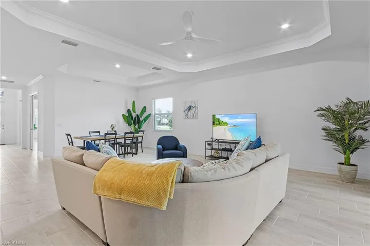 Living room featuring ceiling fan, crown molding, and a tray ceiling