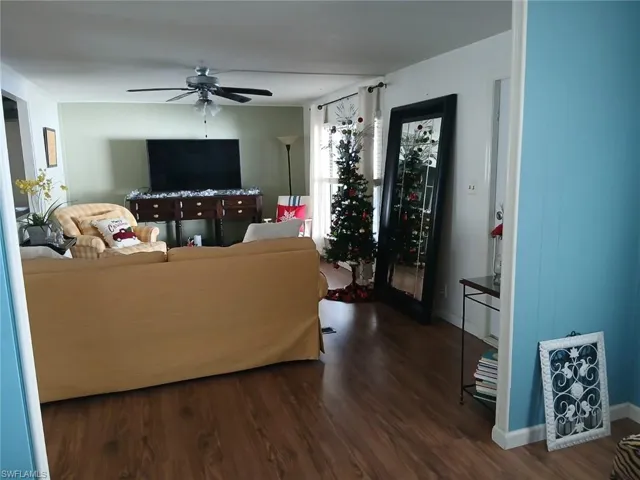 Living room with dark wood-type flooring and a ceiling fan
