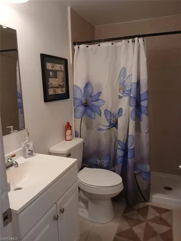 Full bathroom featuring a stall shower, vanity, and light tile patterned flooring