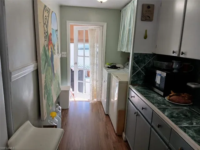 Kitchen with gray cabinets, dark wood-type flooring, separate washer and dryer, and stainless steel microwave