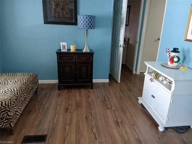 Bedroom with dark wood-style flooring and baseboards