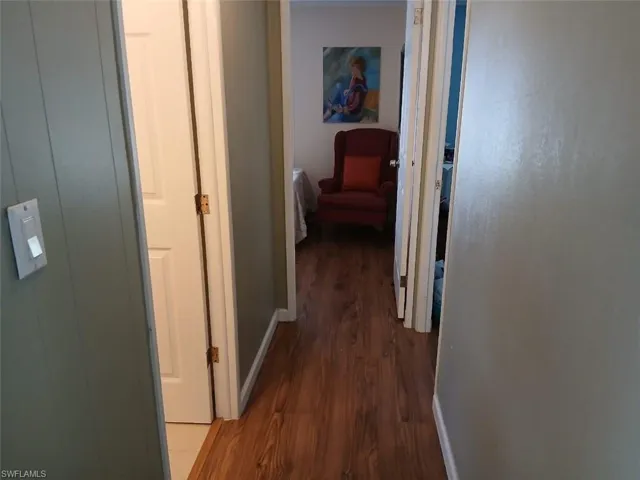 Corridor featuring dark wood-style floors and baseboards