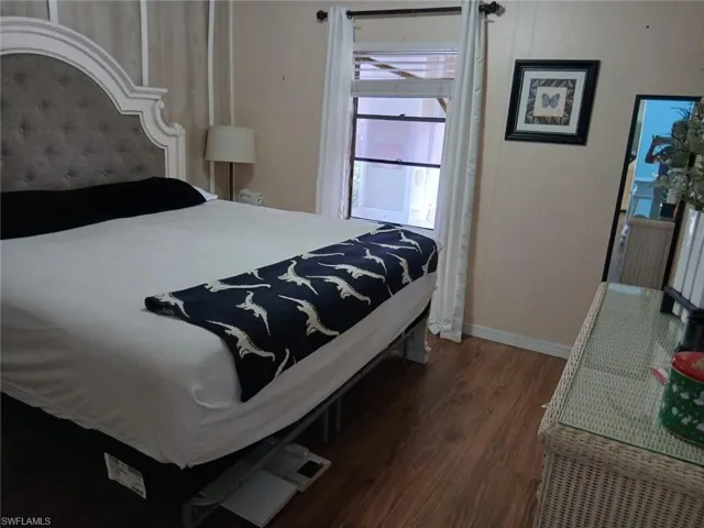 Bedroom featuring dark wood-style flooring and baseboards